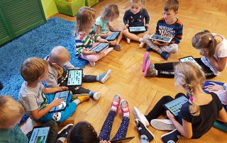 Dzieci bawią się tabletami w kółku w ramach dodatkowych zajęć w Owocowym Przedszkolu na Ursynowie.